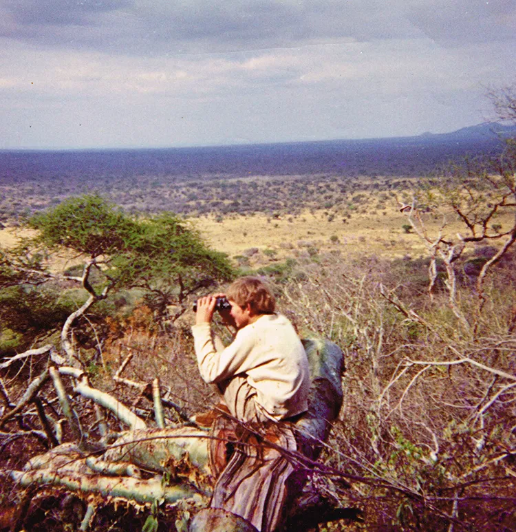 1970 Selous, Tanzania, Simon aged 13 perched on a large tree branch looking out for elephants from a Kopje.